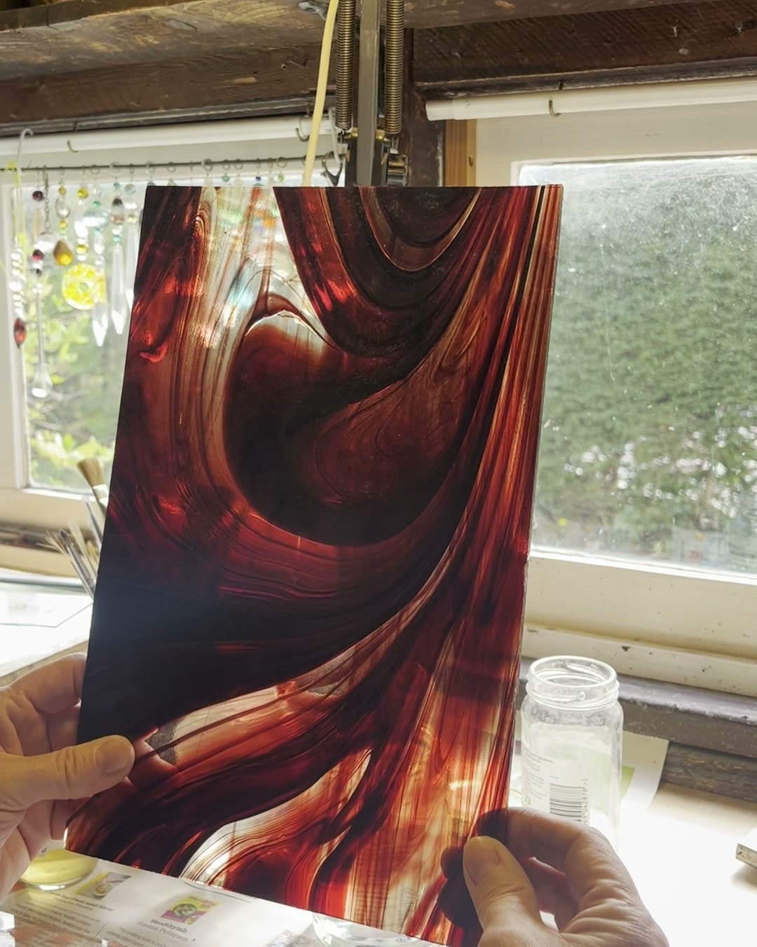 A sheet of streaky red glass held up to the workshop window