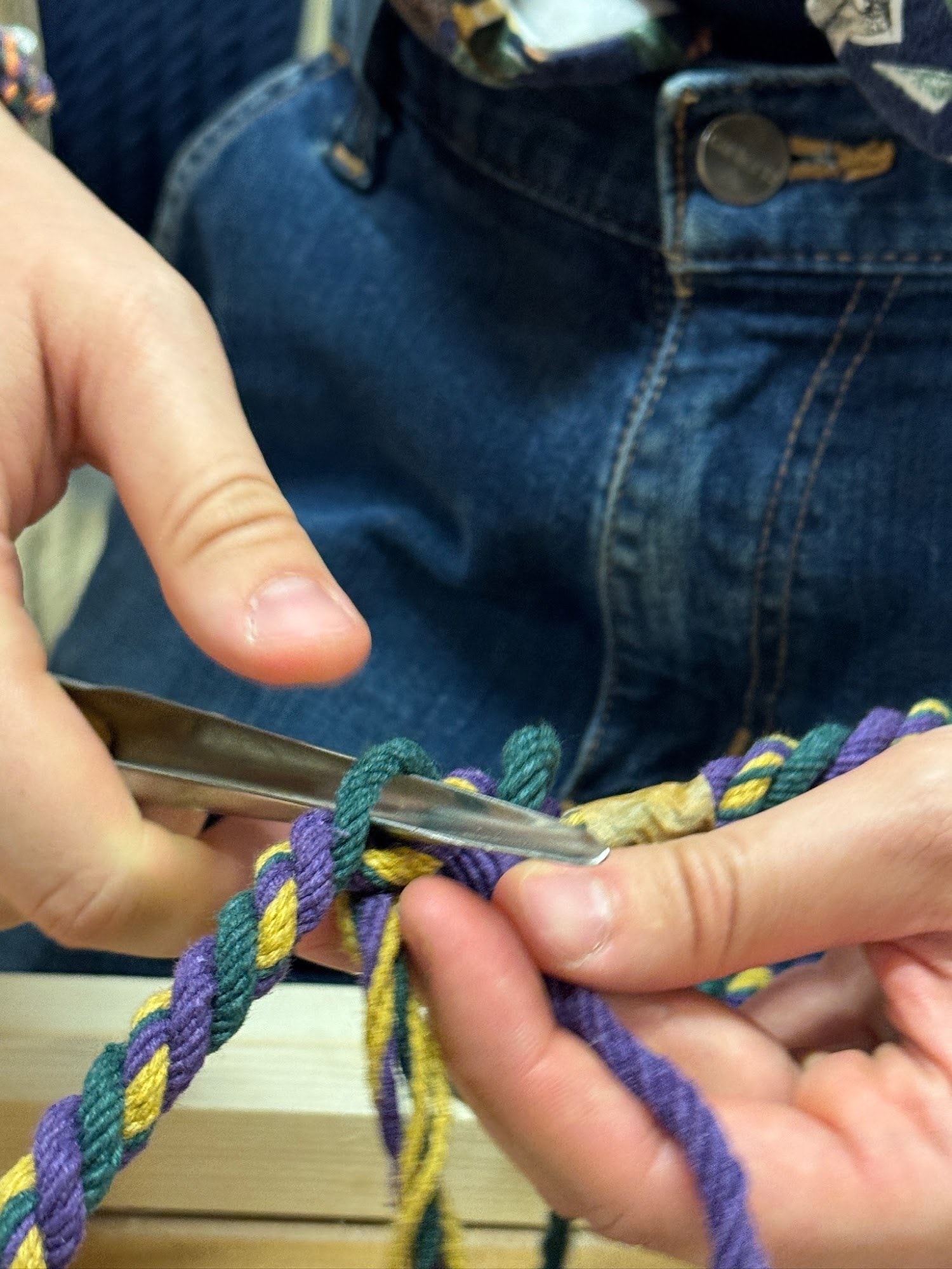 Hands using a steel fid to splice a purple, green and yellow rope lead