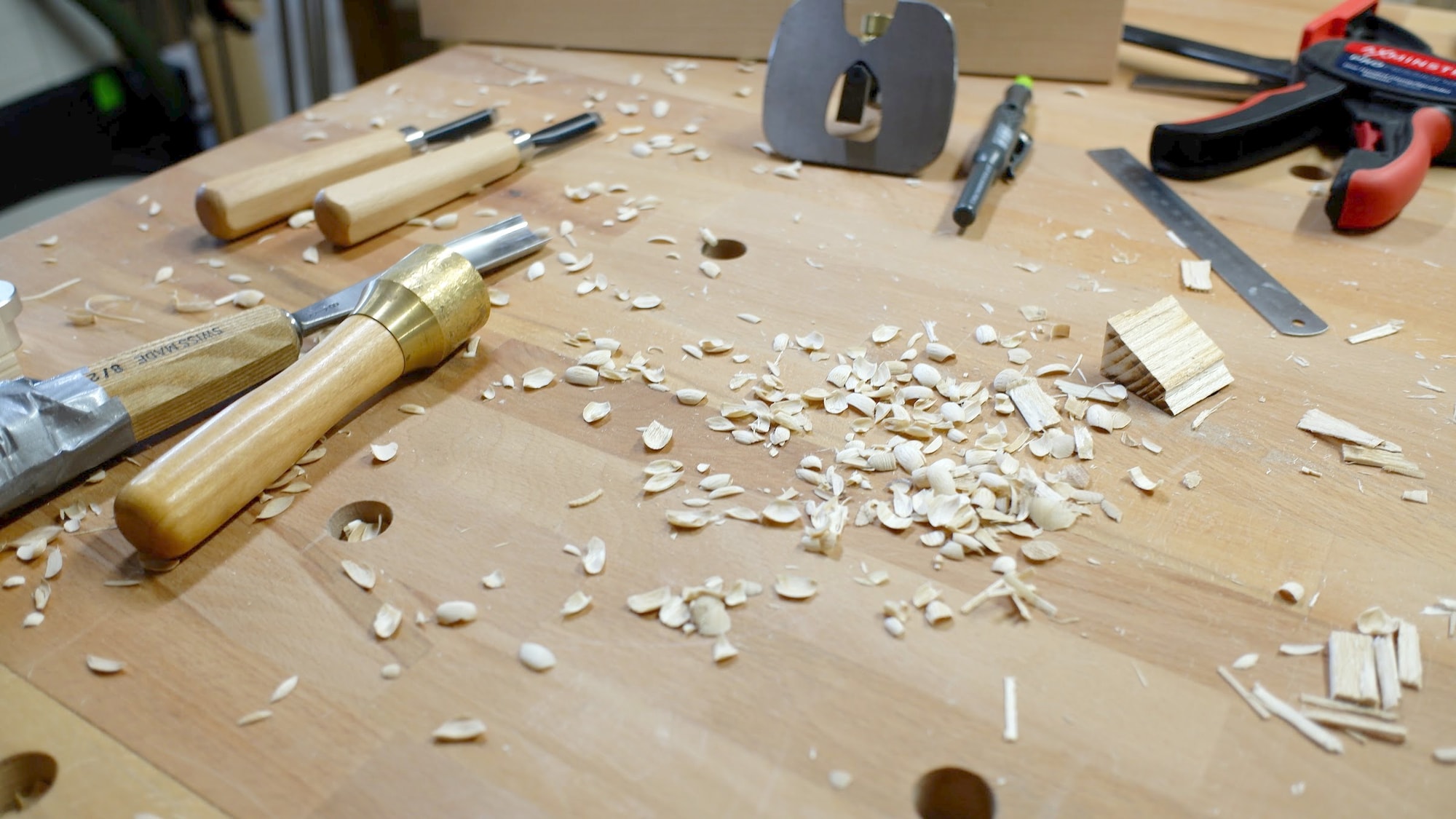 Carving gouges with pale wood shavings scattered across a beech workbench