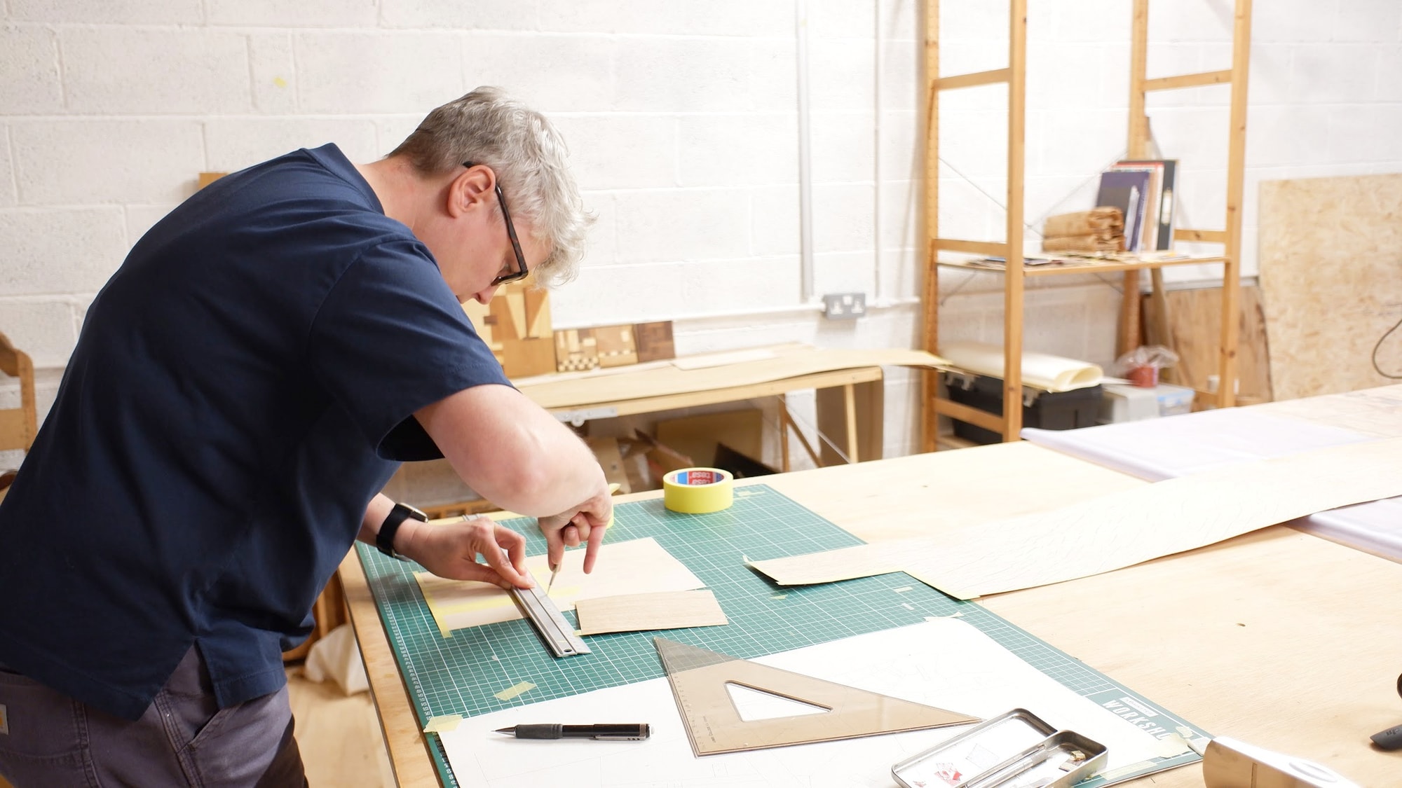 Claire Broad marking a sheet of veneer against a steel rule on her cutting table