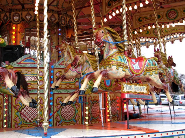 Carved and hand-painted horses on an old-time fairground roundabout, with gilded scrollwork behind