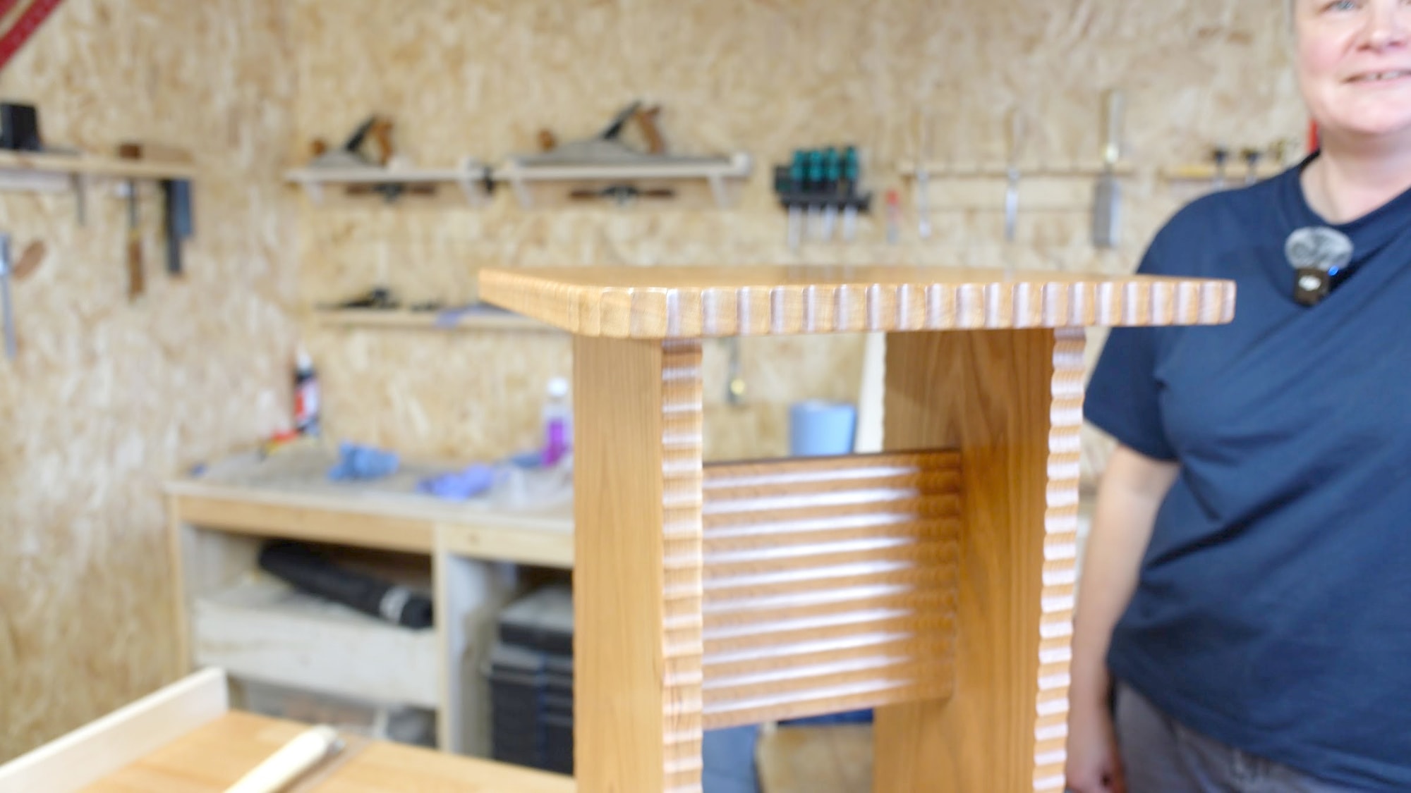 Close detail of the hand carved scalloped edge and fluted side of a cherry side table