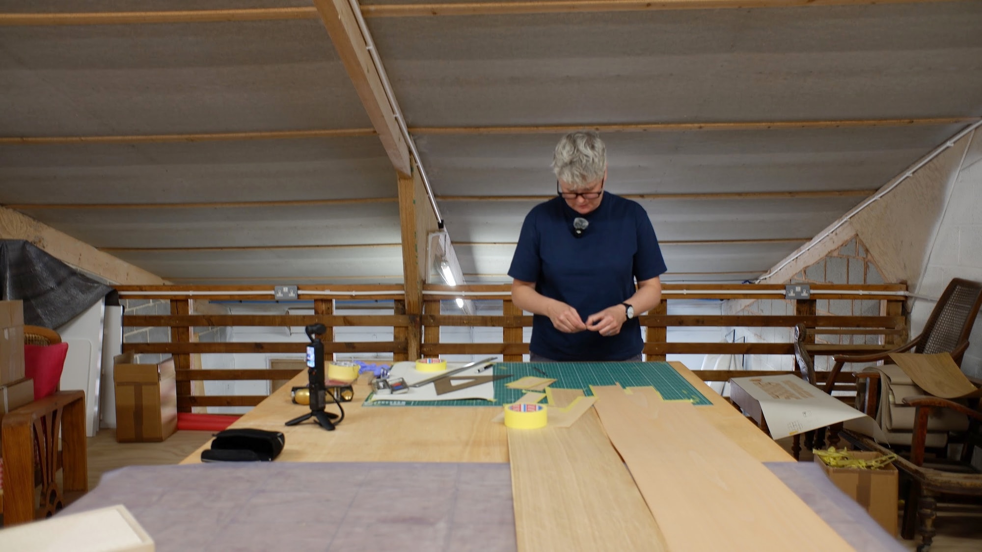 Claire Broad at a long veneer table in the attic of her workshop under the roof beams
