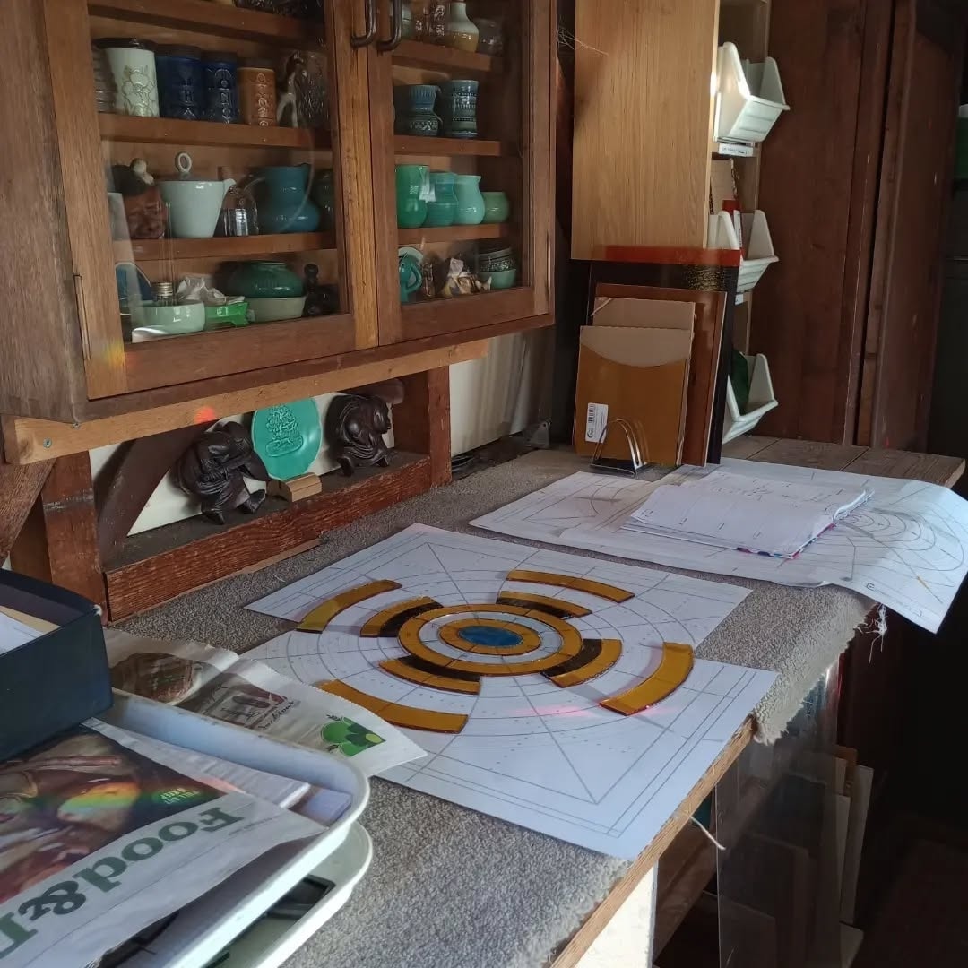 A part-built stained glass panel laid out on its paper cartoon on the workshop bench