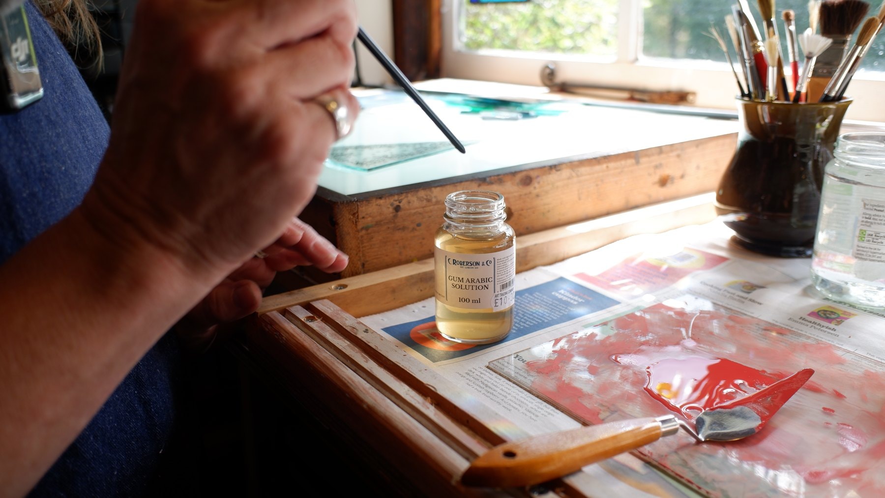 A hand painting fine detail onto glass with a long thin brush